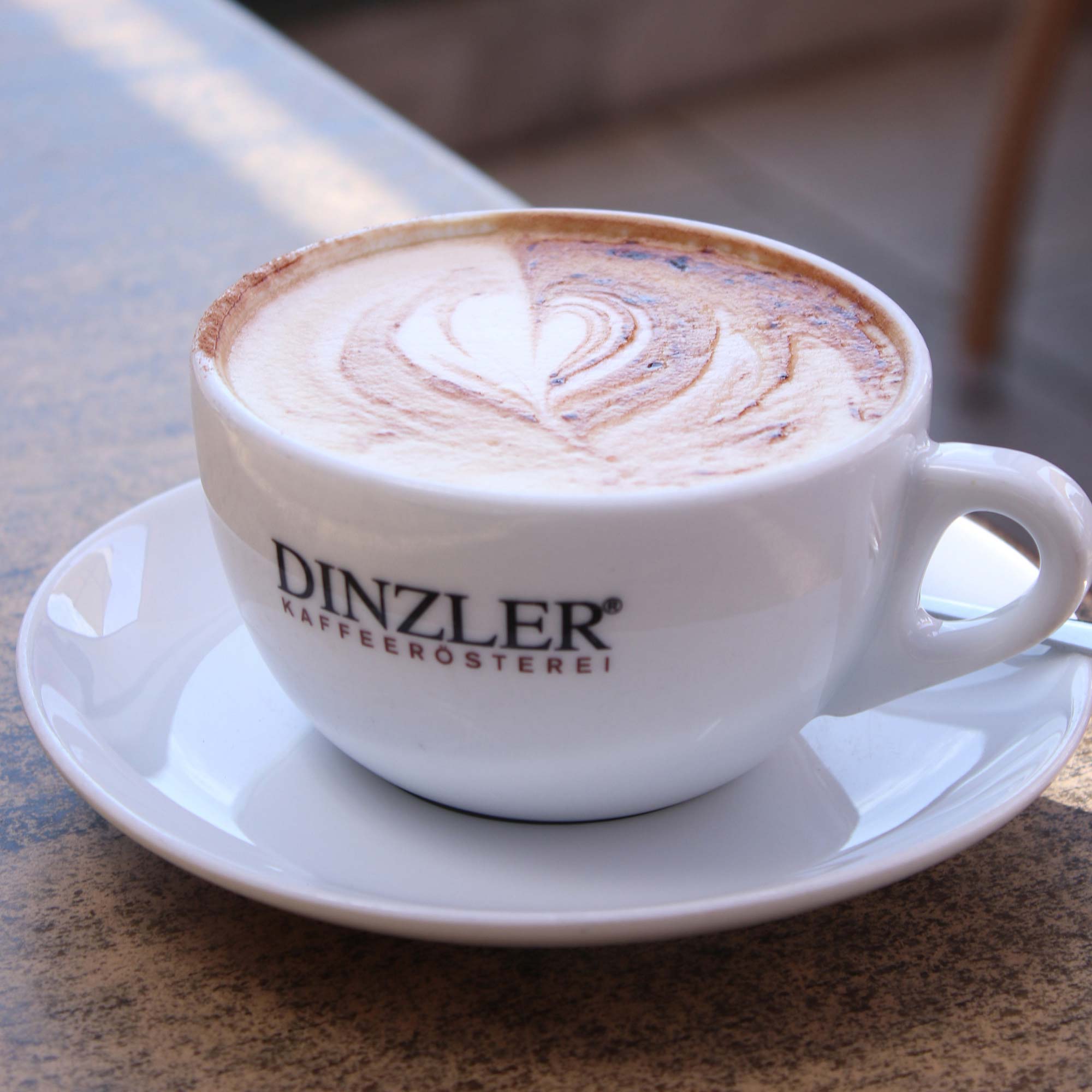 Cappuccino mit Herz als Latte Art auf der Terrasse